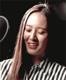 a woman wearing a striped shirt is laughing with her hand over her mouth