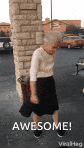 an elderly woman is dancing in front of a brick wall and a trash can .