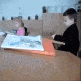 a boy and a girl are sitting at a desk with books