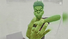 a young man with a green face is holding a green object in his hand .