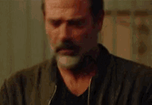 a man with a beard and mustache is wearing a black jacket and a black shirt .