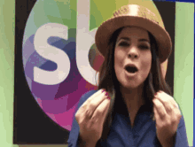 a woman wearing a hat stands in front of a sign that says ' sb '