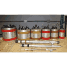 a bunch of metal cylinders are lined up on a wooden surface