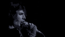 a close up of a person singing into a microphone in the dark .