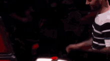 a man is pressing a red button on a table in a dark room .