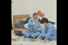 two men in blue pajamas are playing with toys on the floor and one has a hat that says ' ts ' on it