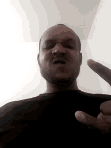a man in a black shirt is giving a middle finger