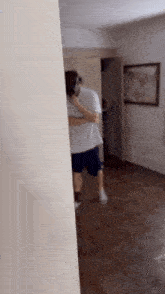 a man in a white shirt and shorts is standing in a room