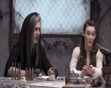 a man and a woman are sitting at a table with bullets on it and a sign that says ' bullets '