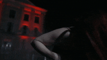a woman in a black dress is standing in front of a red building