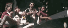 a group of young men are sitting in the back of a car with a carton of lychee juice in the background