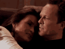 a man and a woman are laying on a couch and looking into each other 's eyes .