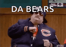 a man wearing a chicago bears jacket is pointing at the camera .