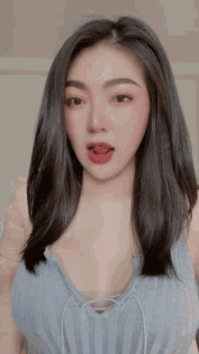a woman with long black hair is wearing a gray tank top