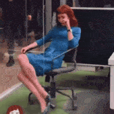 a woman in a blue dress is sitting in an office chair