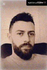 a man with a beard is sitting in a chair and looking at the camera