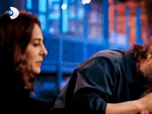 a man kisses a woman on the cheek in front of a sign that says d on it