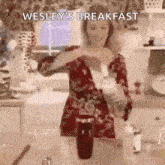 a woman is pouring a drink into a glass in a kitchen with the caption `` wesley 's breakfast '' .