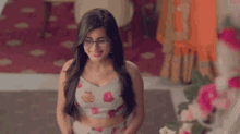 a woman wearing glasses and a floral crop top smiles