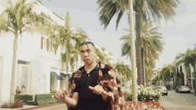 a man in a fur coat is walking down a street with palm trees in the background
