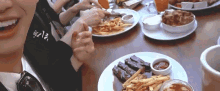 a group of people are sitting at a table with plates of food including a plate of ribs