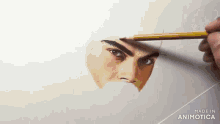 a person is drawing a man 's face with a pencil on a piece of paper .