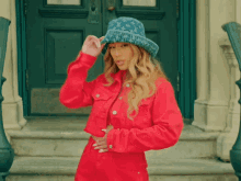 a woman wearing a louis vuitton hat and red jacket