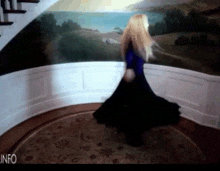 a woman in a blue dress is dancing in front of a painting that says info on the bottom