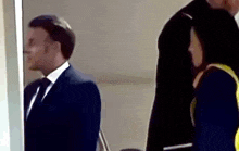 a man in a suit and tie is standing next to a woman in a yellow jacket .