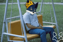 a man is sitting on a swing with a fox mask on his head