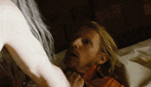 a man with long blonde hair laying on a bed