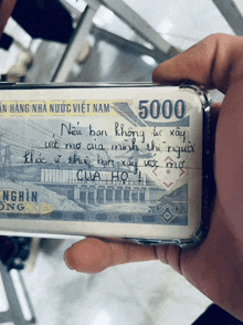 a person is holding a 5000 vietnamese banknote
