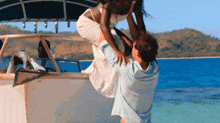 a man is holding a woman on a boat in the ocean