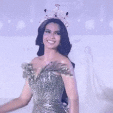 a woman wearing a crown and a dress is smiling on a stage .
