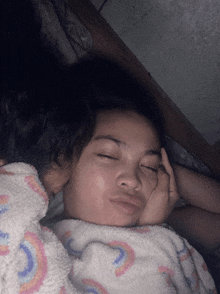 a girl with her eyes closed is wrapped in a blanket with a rainbow pattern