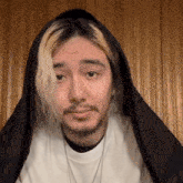 a man with blonde hair and a beard is wearing a black hooded jacket