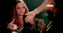 a woman with pink hair is reaching out her hand to another woman .