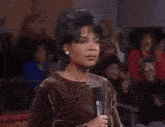 a woman is standing in front of a crowd with her mouth open .