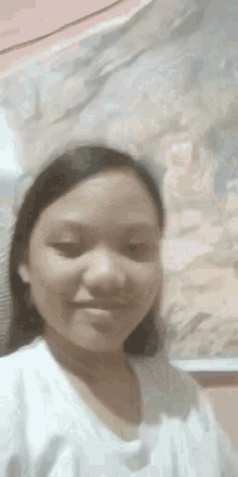 a young girl is standing in front of a painting and smiling at the camera .