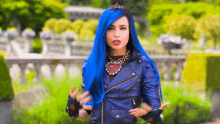 a woman with blue hair and a leather jacket is wearing a tiara and gloves .
