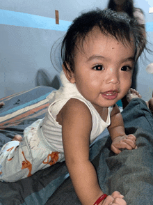 a baby is crawling on a bed and has a red wristband