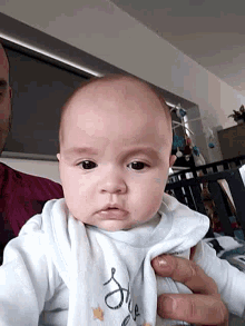 a baby is being held by a man and the baby is wearing a shirt that says " daddy "