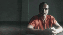 a man in an orange shirt sits at a table with the words you wanna be a friend of the cartel