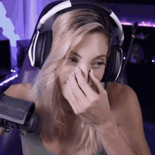 a woman wearing headphones and a microphone is covering her mouth .