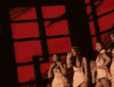 a group of women standing in front of a red background