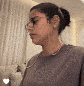 a woman wearing glasses and a chain around her neck has a heart in the corner