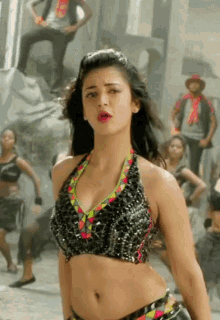 a woman in a crop top is dancing in front of a group of people