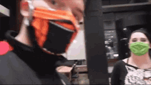 a man and a woman wearing masks are standing next to each other in a room .