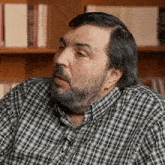 a man with a beard is wearing a plaid shirt and earrings