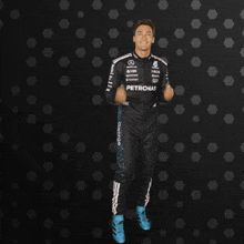 a man in a petronas suit is standing with his hands outstretched